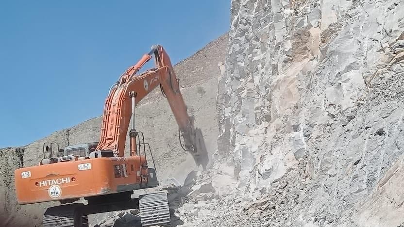 Excavator with a rock breaker cutting a hillside on a National Highway package in Balochistan